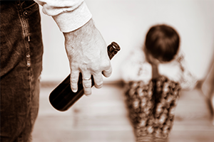 Sepia-toned close-up of an adult holding a child’s hand as they walk together; the child carries a bottle, creating a tender but somber mood.